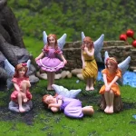 A delightful arrangement of five colorful fairy figurines showcasing different poses amidst a lush green garden setting, complete with a stone wall and vibrant flowers.