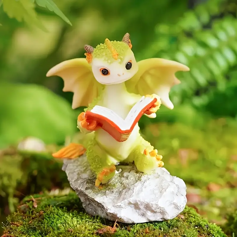A charming green dragon figurine with wings, perched on a rock, engrossed in a book amidst a lush, green background.