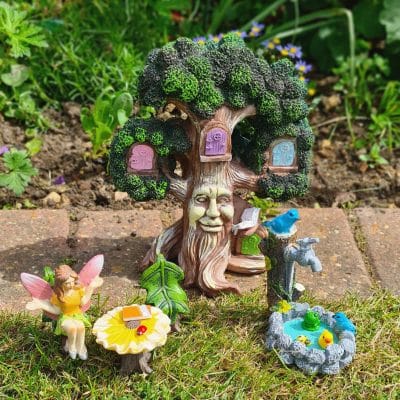 A charming fairy garden with a smiling tree, colorful doors, a fairy sitting at a flower table, and a small pond with birds and frogs.